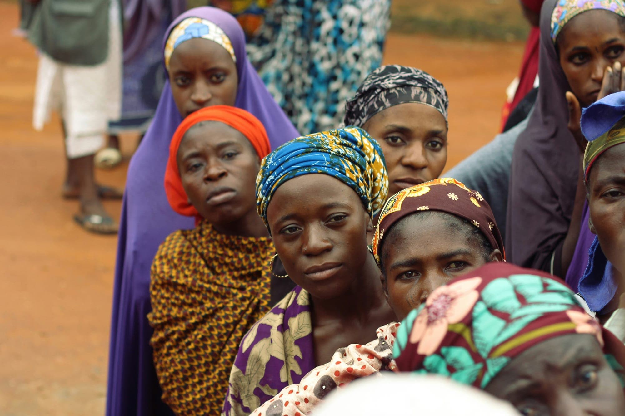 A line of women in colourful headwraps waiting to vote
